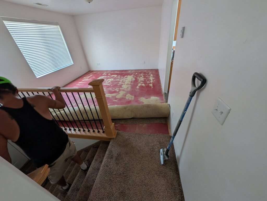 Worker removing flooring during a Brigham City investment property renovation by The Nelsons Crew