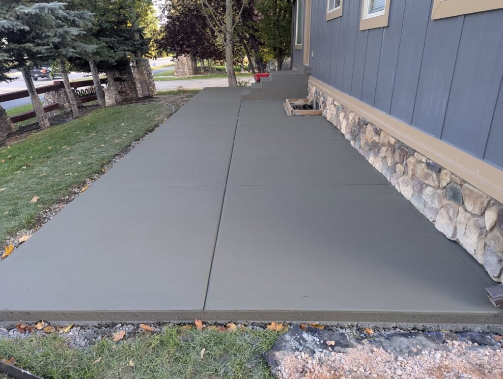 Finished concrete patio and walkway installed beside a home by The Nelsons Crew