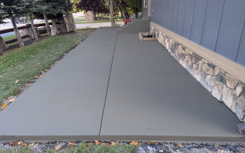Finished concrete patio and walkway installed beside a home by The Nelsons Crew